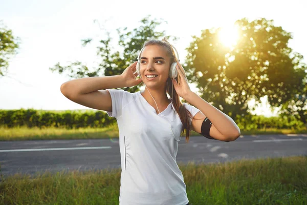 道路上でジョギングする前にヘッドセットを休ませる女の子ランナー — ストック写真