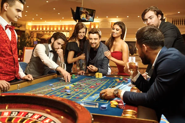 Gente feliz jugando poker ruleta en el casino —  Fotos de Stock