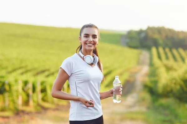 Brunetka dziewczyna biegacz z butelką wody jest w treningu — Zdjęcie stockowe