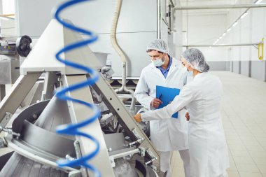 Gıda fabrikasında maskeler içinde teknoloji müfettişi.
