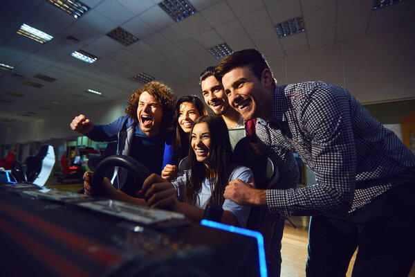 A group of friends playing arcade machine.