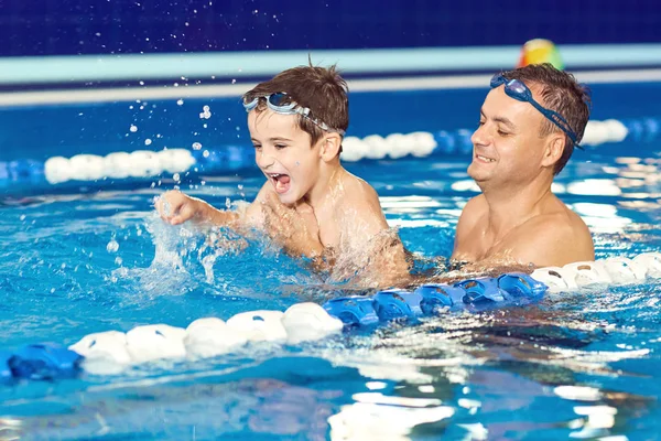 Vader en zoon spelen in het water in een zwembad. — Stockfoto
