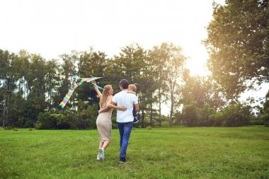 Mutlu aile parkı çimenlerde aracılığıyla bir uçurtma ile çalışır.