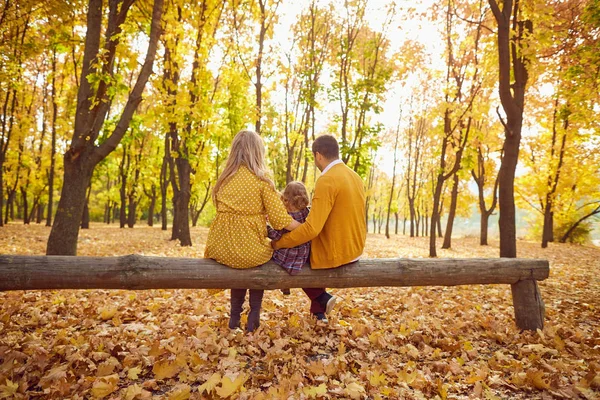 Aile sonbaharda bir park bankında oturuyor..
