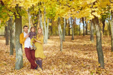 Sonbaharda parkta bebekle oynayan aile.