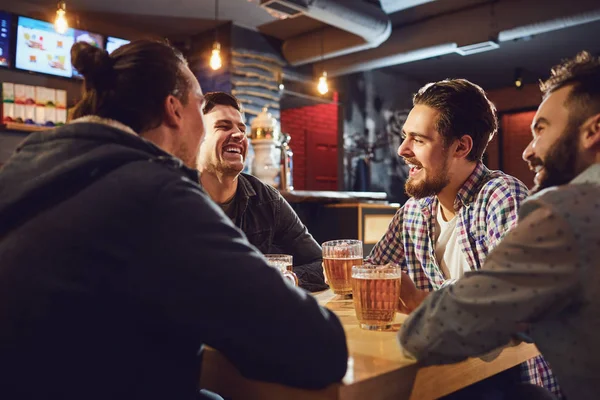 Os amigos falam, bebem cerveja num bar . — Fotografia de Stock