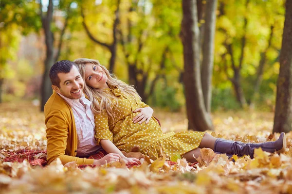 Para siedzi na liściach w jesiennym parku. — Zdjęcie stockowe