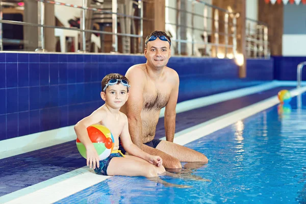 Отец и сын плавают в бассейне — стоковое фото