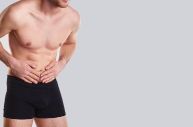 Bir erkek iç çamaşırı midesi ellerini tutar..