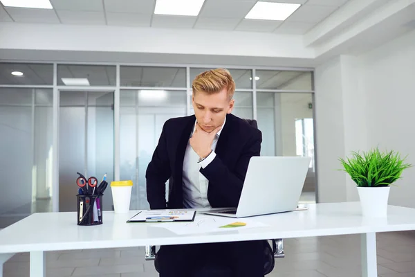 Un homme d'affaires sérieux pense s'asseoir à une table sur un lieu de travail dans un bureau . — Photo