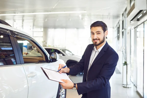 A car dealer is holding documents on the sale of a car. — Stock Photo, Image