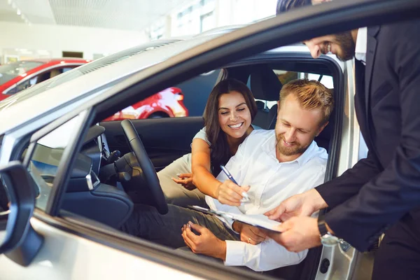 Um casal compra um carro em um showroom de carro. — Fotografia de Stock