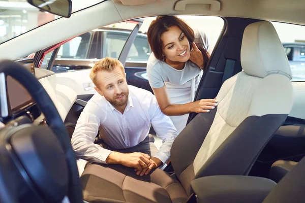 Jovem casal escolher um novo carro no showroom . — Fotografia de Stock