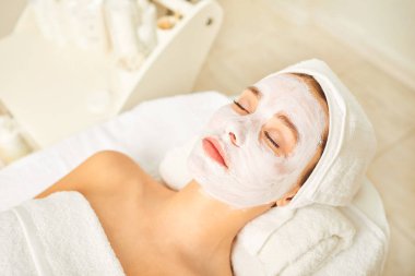 Spa salonunda bir kadının yüzünde kozmetik maske.