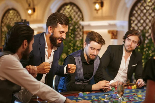 Ein junger Mann freut sich, im Casino zu gewinnen. — Stockfoto