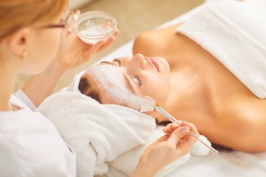 Spa salonunda yüz kozmetik maskesi olan kadın.