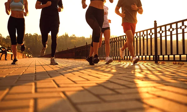 A group of young people runs along the road in the park. — Stock Photo, Image