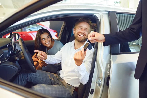 Um casal feliz comprou um carro novo em um showroom do carro . — Fotografia de Stock