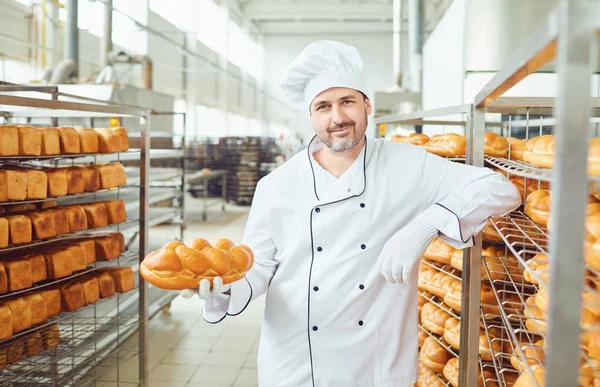 Un panettiere in una panetteria contro gli scaffali del pane . — Foto Stock
