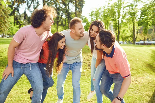 Группа друзей смеётся, обнимаясь в парке — стоковое фото