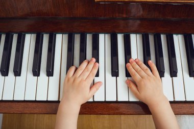 Çocuk piyano tuşları üzerinde eller.