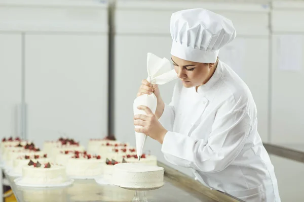 Konditor dekoriert Kuchen in Konditorei. — Stockfoto