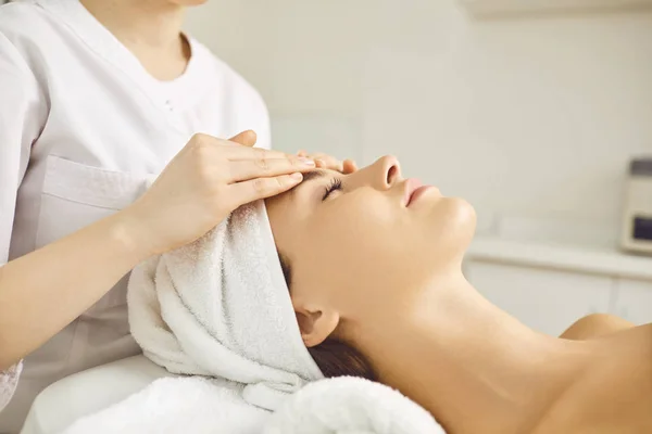 Gezichtsmassage voor een jonge vrouw liggend in een schoonheidssalon. — Stockfoto