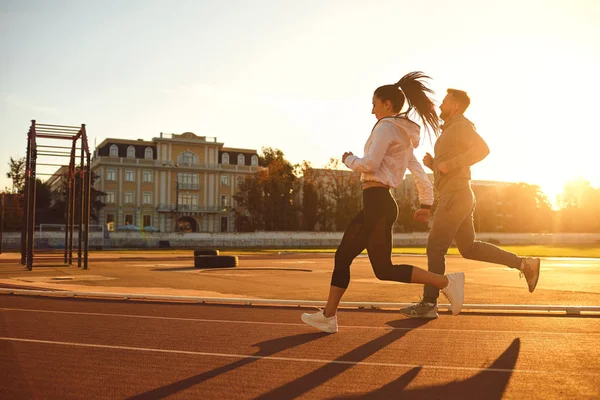 Athletic couple runs in the morning at the stadium. — Stock Photo, Image