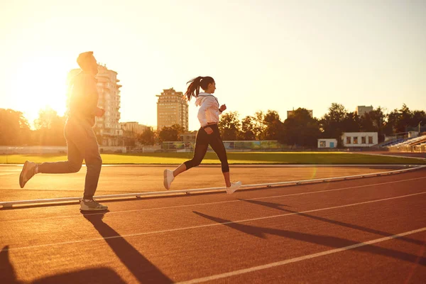 Young man and woman runners run in the morning at dawn. — Stock Photo, Image