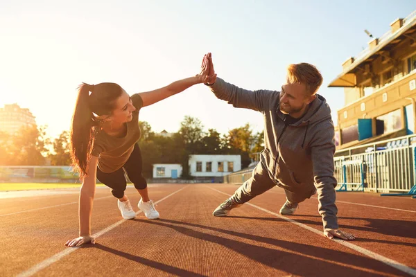 Young couple doing pushups in the stadium — Stock Photo, Image