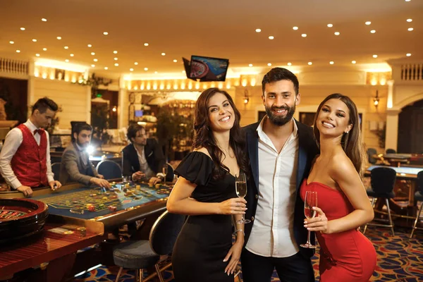 Schöne Glamour Menschen lächeln gegen im Casino Poker Roulette. — Stockfoto