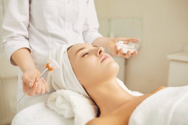 Bir kozmetolojist bir kadına maske uygular..