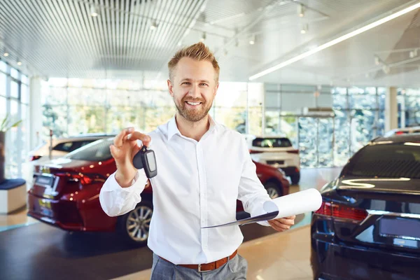 Obchodník s auty drží klíče v ruce v showroomu. — Stock fotografie