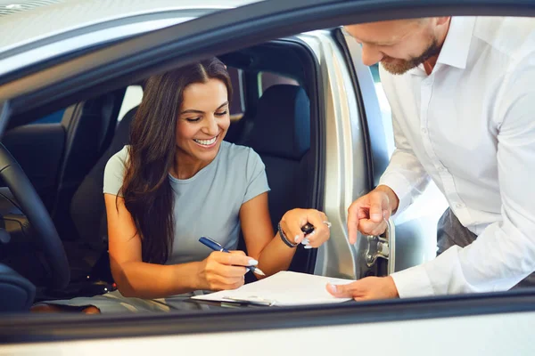 Mladá žena kupuje auto v autosalónu. — Stock fotografie