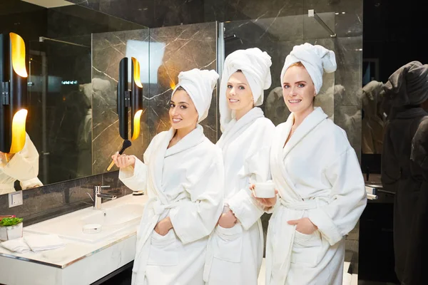 Mujeres jóvenes con albornoz blanco en el baño en una fiesta de spa — Foto de Stock