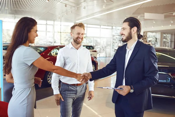 Affari d'auto. Una donna e un venditore di auto fanno una stretta di mano — Foto Stock