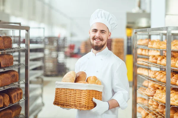 Bearded Baker glimlacht met een mandje brood in het bakhuis — Stockfoto