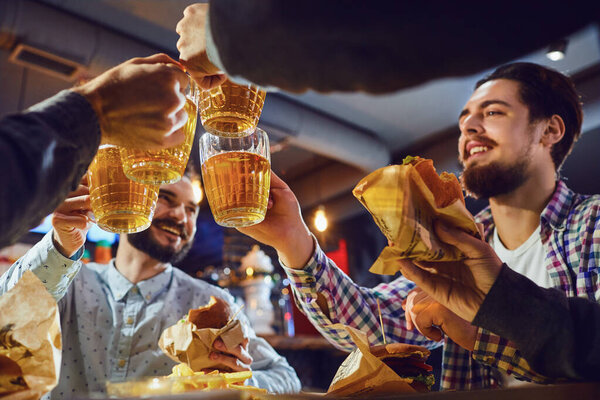 Friends clink glasses with beer in a bar.