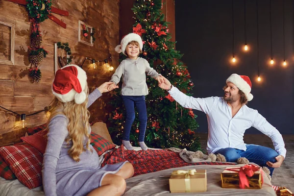 Lachend kind met ouders op bed in kersttijd — Stockfoto