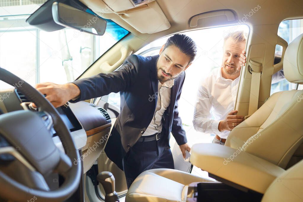 Professional salesmen selling cars at dealership to buyer