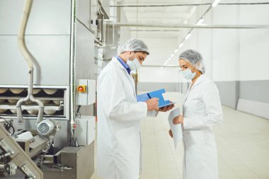 Gıda fabrikasında maskeler içinde teknoloji müfettişi.