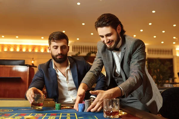 Gruppo uomo in giacca e cravatta a tavolo roulette giocare a poker in un casinò . — Foto Stock