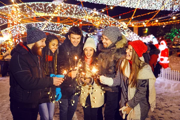 Glückliche Freunde mit Wunderkerzen auf dem Weihnachtsmarkt — Stockfoto