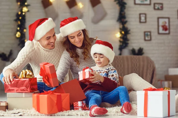 Rodina dává dárky pro dítě doma k Vánocům. — Stock fotografie