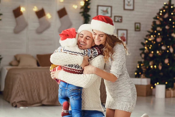 Família com presentes abraçando em casa no Natal . — Fotografia de Stock