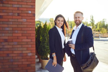 İş adamı ve iş kadını dışarıda gülümsüyor..