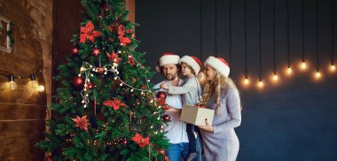 Aile Noel ağacını Noel 'de evde süslüyor.