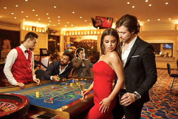 Belo casal glamour contra o fundo da roleta de poker casino . — Fotografia de Stock