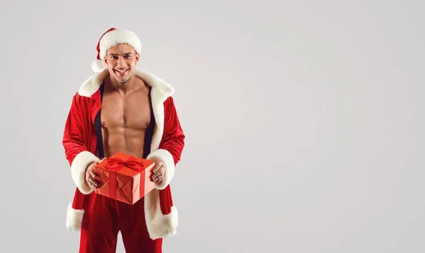 현재를 들고 있는 산타 수트를 입은 근육질의 남자 — 스톡 사진