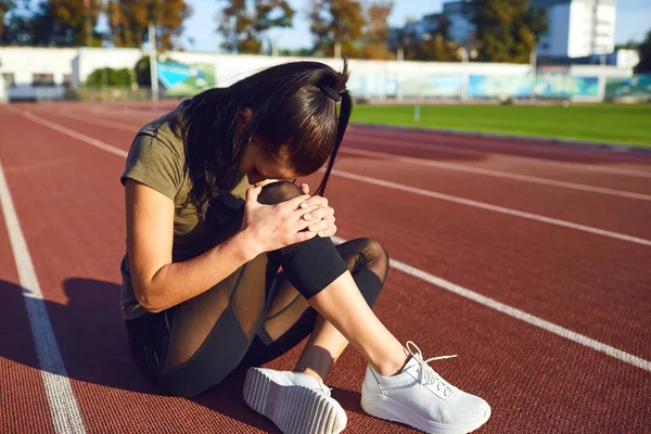 Lesão no joelho em treinamento.Menina machucou sua perna durante o exercício . — Fotografia de Stock